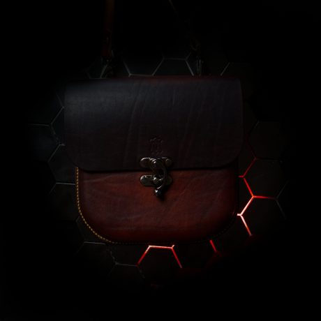 wet mould veg-tan leather bag, on dark background